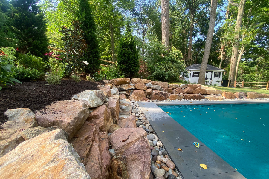 Stunning Outdoor Space Transformation with Boulder Retaining Walls and Flagstone Walkway 11 boulder retaining wall around garden by pool